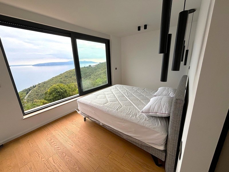 Chambre lumineuse avec grande fenêtre et vue mer