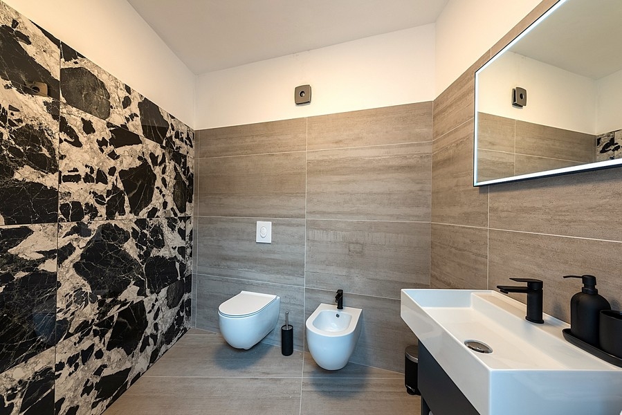 Salle de bains moderne avec grands carreaux, lavabo et bidet
