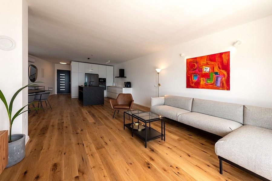 Salon moderne avec grand canapé, télévision et accès à la terrasse