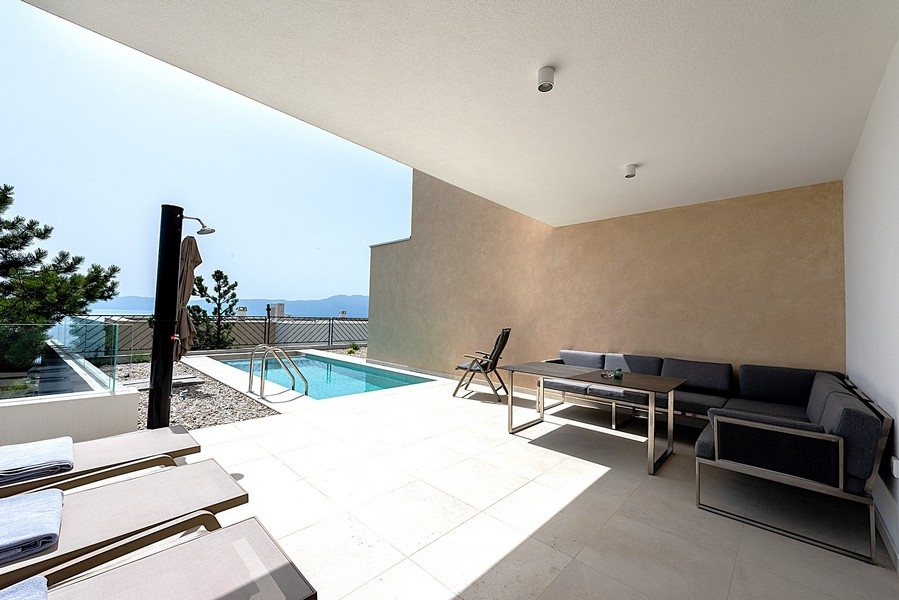 Terrasse avec piscine, chaises longues et vue mer