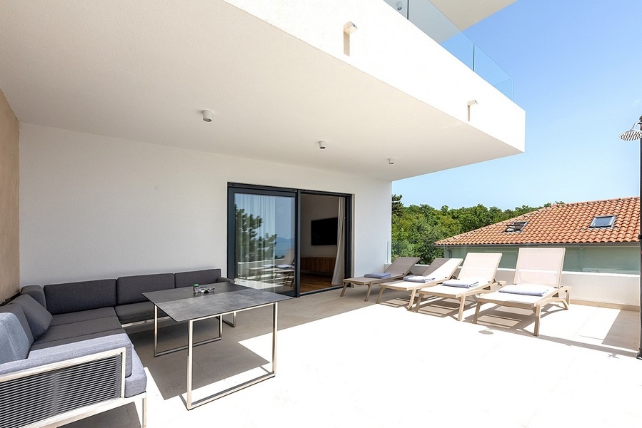 Terrasse couverte avec mobilier lounge et bains de soleil