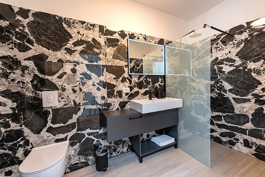 Salle de bains moderne avec mur en marbre noir et douche à l'italienne