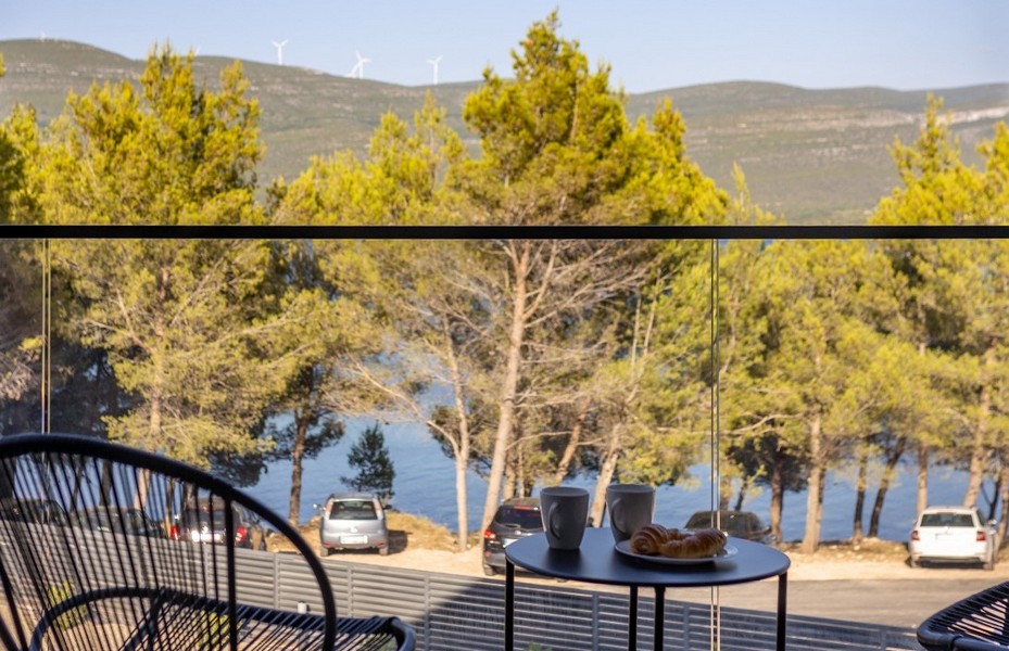 Table de balcon avec croissants et vue à travers les pins sur la baie