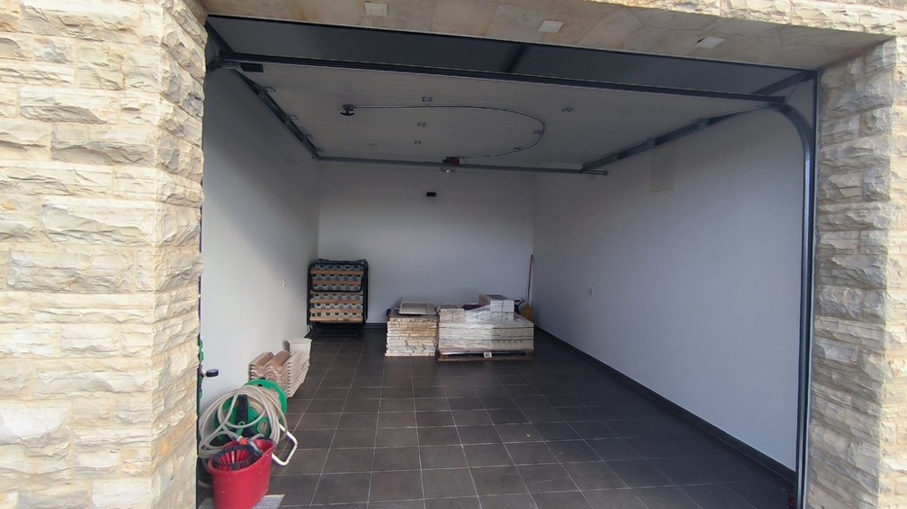 Garage avec parement en pierre et sol carrelé