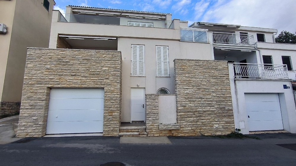 Maison avec murs en pierre naturelle et garage au bord de la route