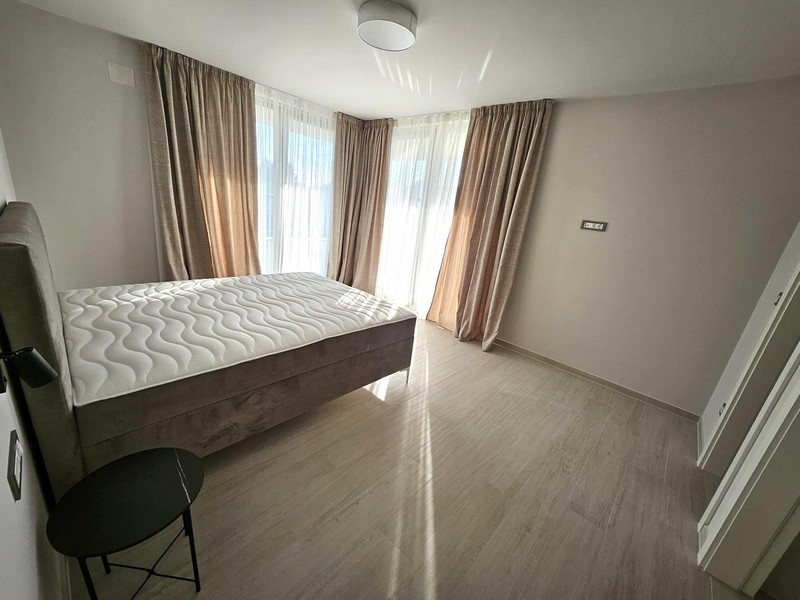 Chambre lumineuse avec lit double, rideaux et portes de balcon