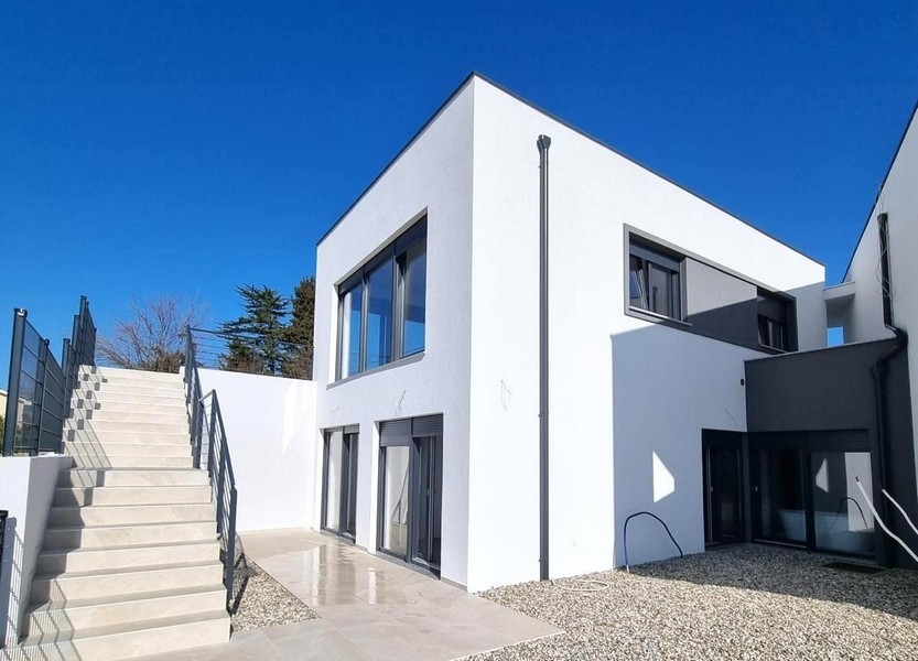 Immeuble neuf blanc avec escalier extérieur et massif de gravier