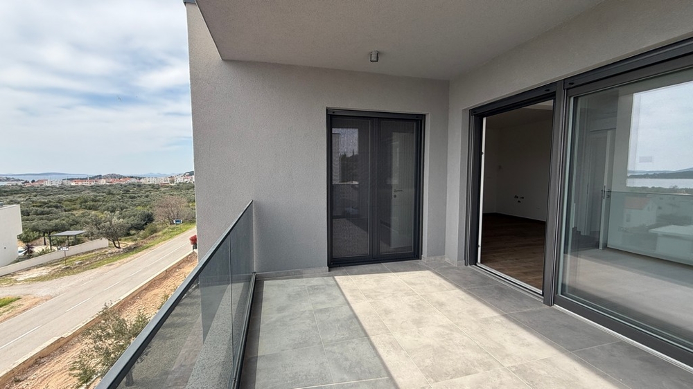 Balcon couvert avec garde-corps en verre et accès au séjour