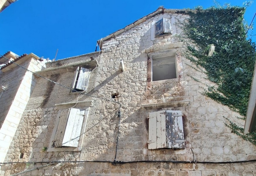 Ancienne maison en pierre avec volets patinés et lierre