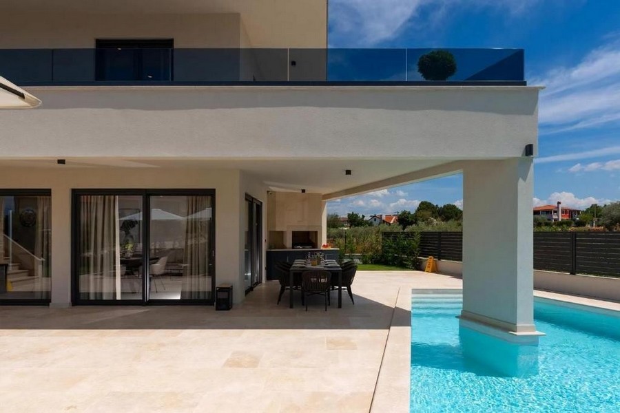 Terrasse couverte avec table à manger au bord de la piscine