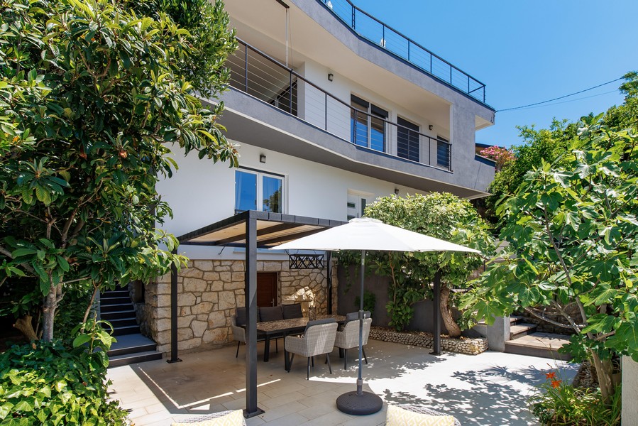Terrasse de jardin couverte avec coin salon et mur en pierre naturelle