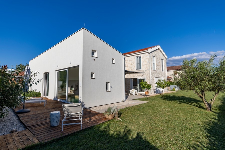 Deck en bois avec transats à côté de l'annexe blanche dans le jardin
