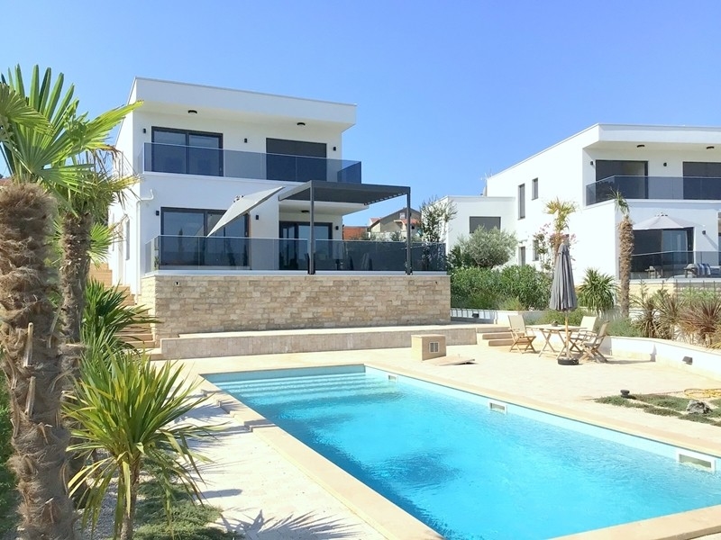 Villa avec voile d'ombrage et piscine entre les palmiers