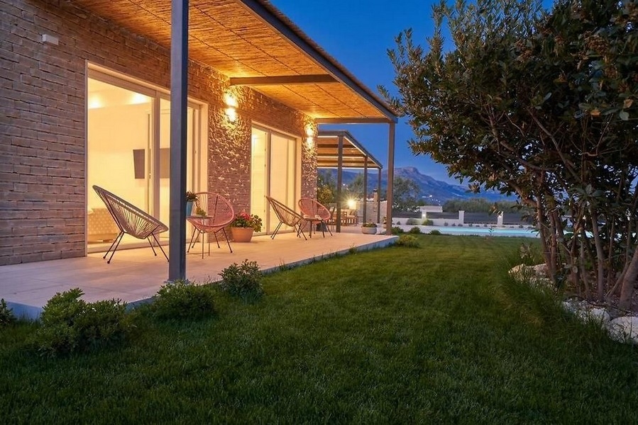 Véranda éclairée avec fauteuils en rotin et piscine à la lumière du soir