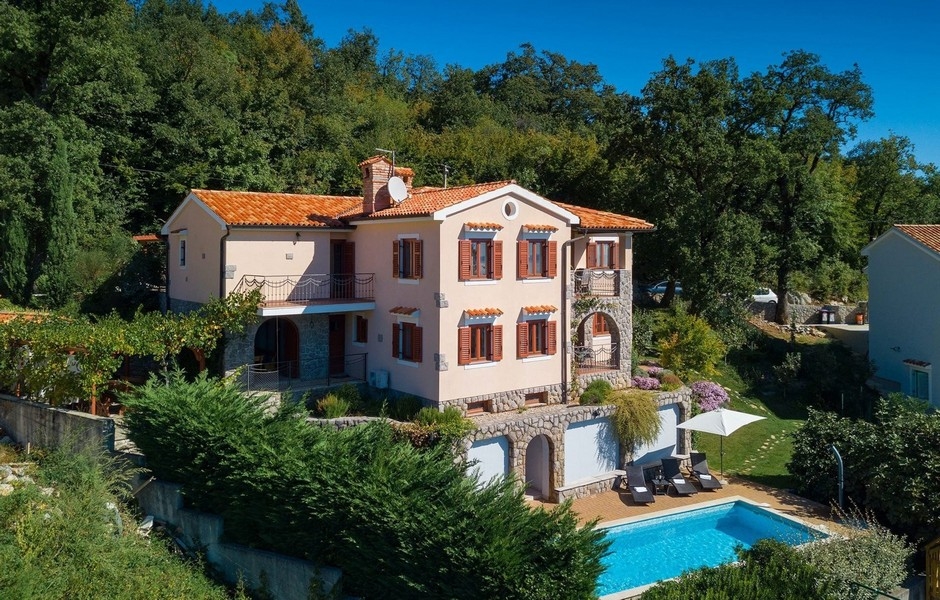 Villa rose avec toit de tuiles et piscine à la lisière de la forêt