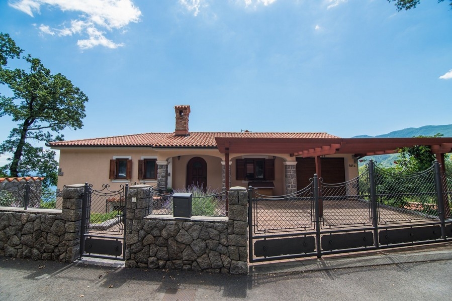Vue de face de la villa avec allée d'accès et portail