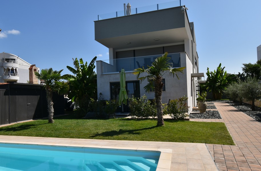 Villa moderne avec palmiers et piscine dans le gazon synthétique