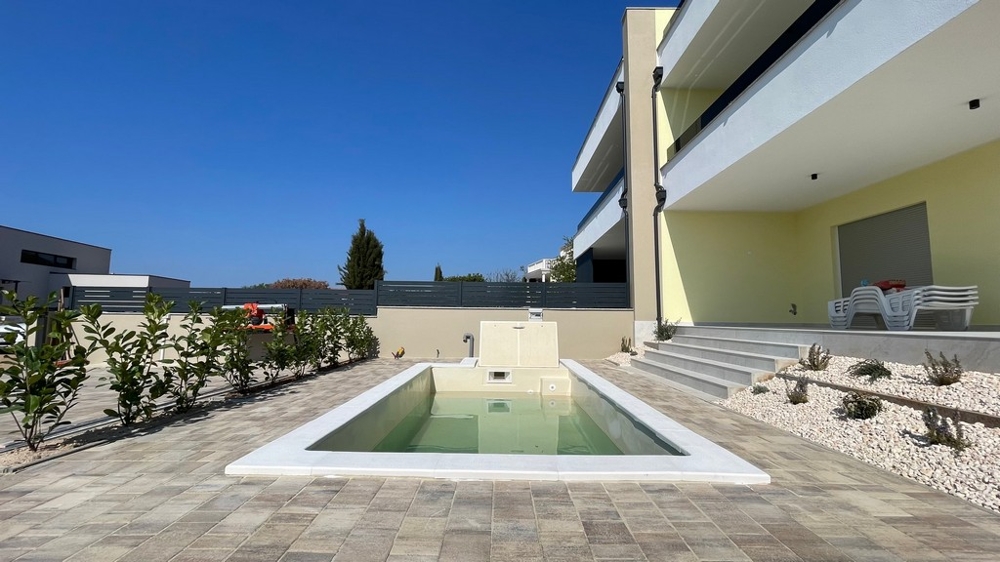 Piscine avec terrasse solarium dans le jardin du bien H3604