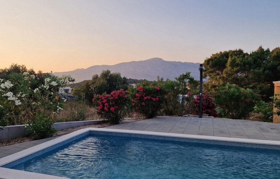 Piscine avec lauriers-roses en fleurs devant la chaîne de montagnes