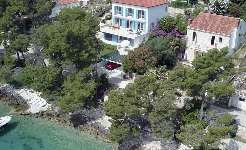 Maison avec volets bleus entre des pins au-dessus de la baie