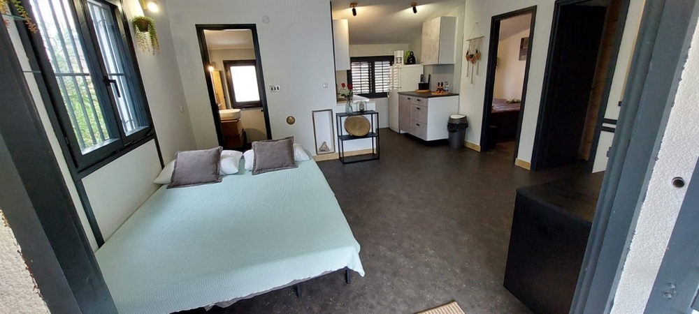 Lit dans la pièce ouverte avec cuisine et salle de bains derrière