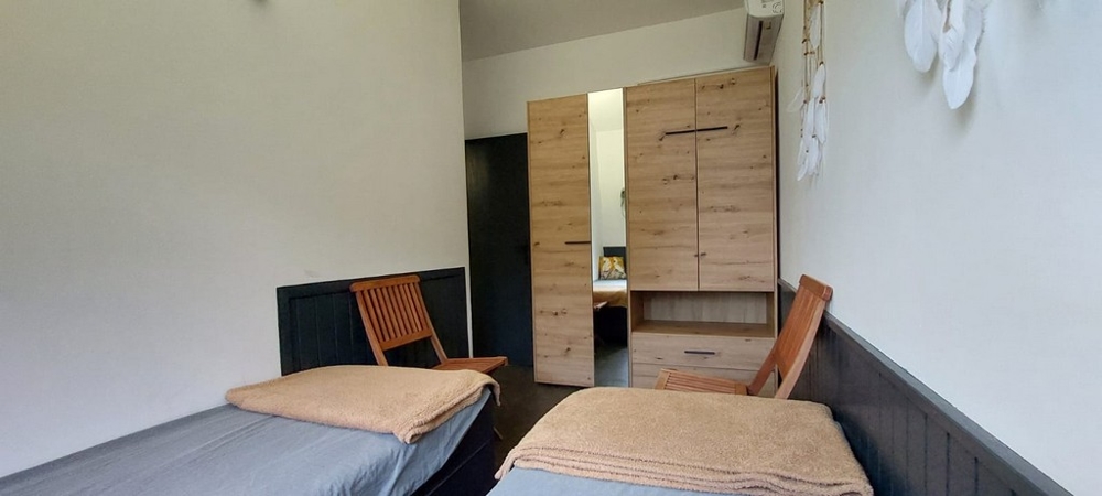 Deux lits simples devant la penderie avec miroir