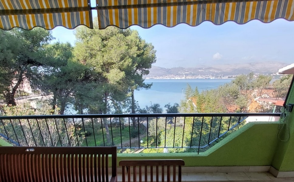 Balcon sous le store avec vue sur la baie à travers les pins