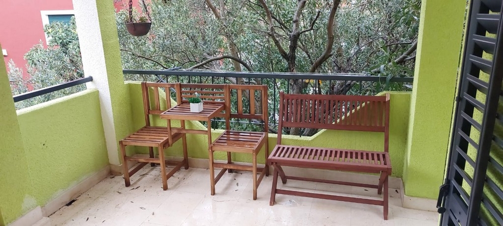 Balcon avec banc en bois et chaises parmi les branches d'olivier