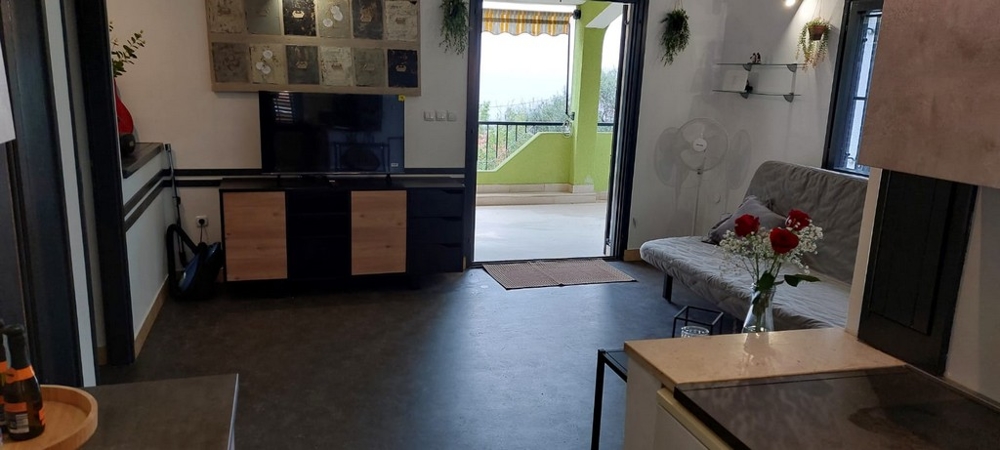 Séjour avec meuble TV et porte ouverte sur le balcon