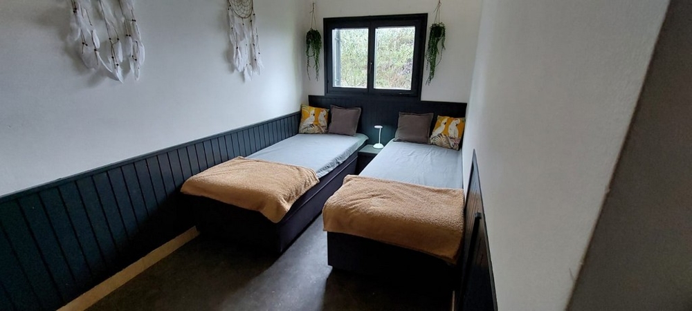 Chambre avec deux lits devant le lambris vert foncé