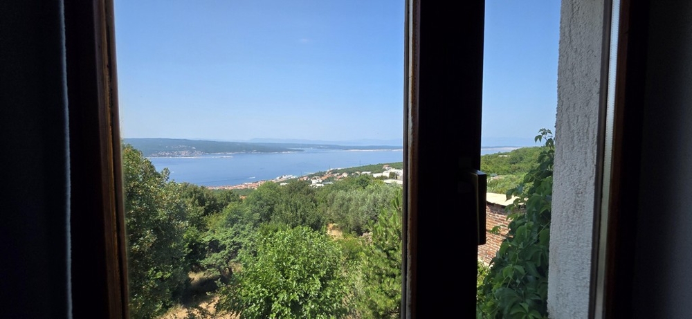 Vue mer par la fenêtre sur un versant verdoyant