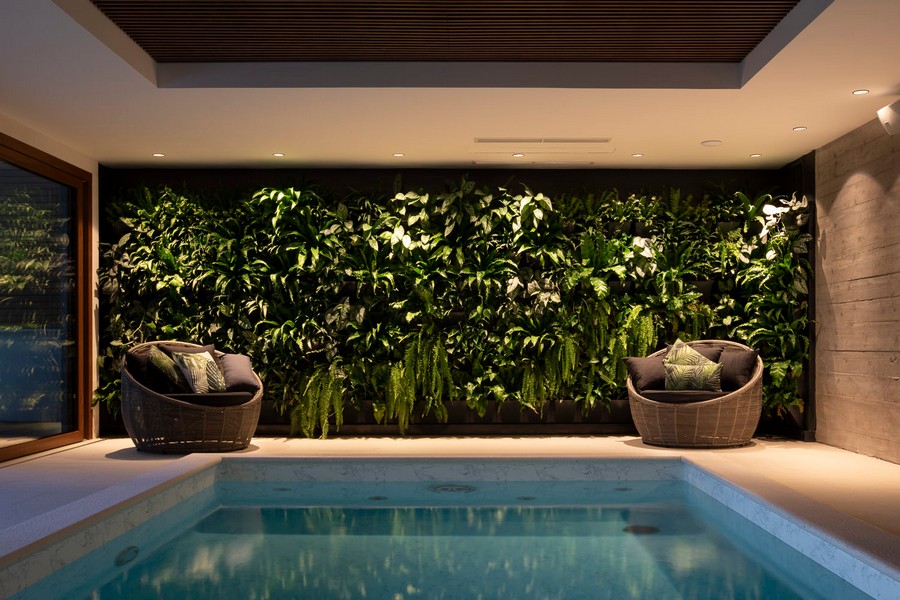Piscine intérieure avec mur végétal et coin salon
