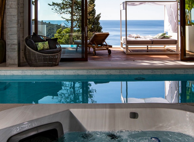 Piscine intérieure avec jacuzzi et vue sur le solarium avec vue mer
