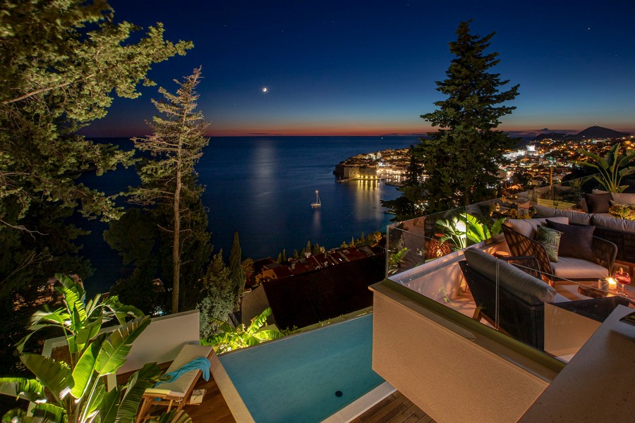 Prise de vue nocturne avec piscine et vue sur la vieille ville illuminée de Dubrovnik.