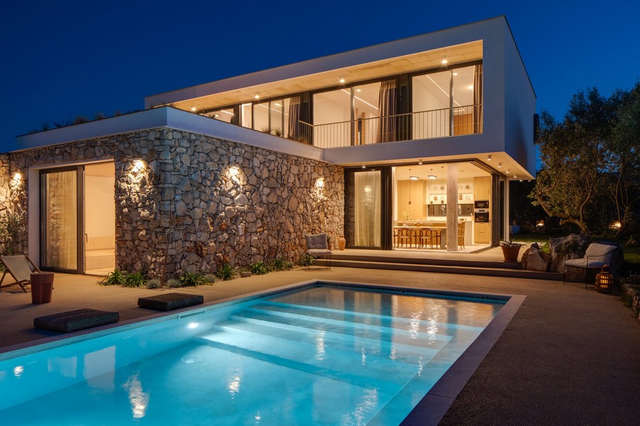 Villa de nuit avec piscine éclairée et façade en pierre naturelle