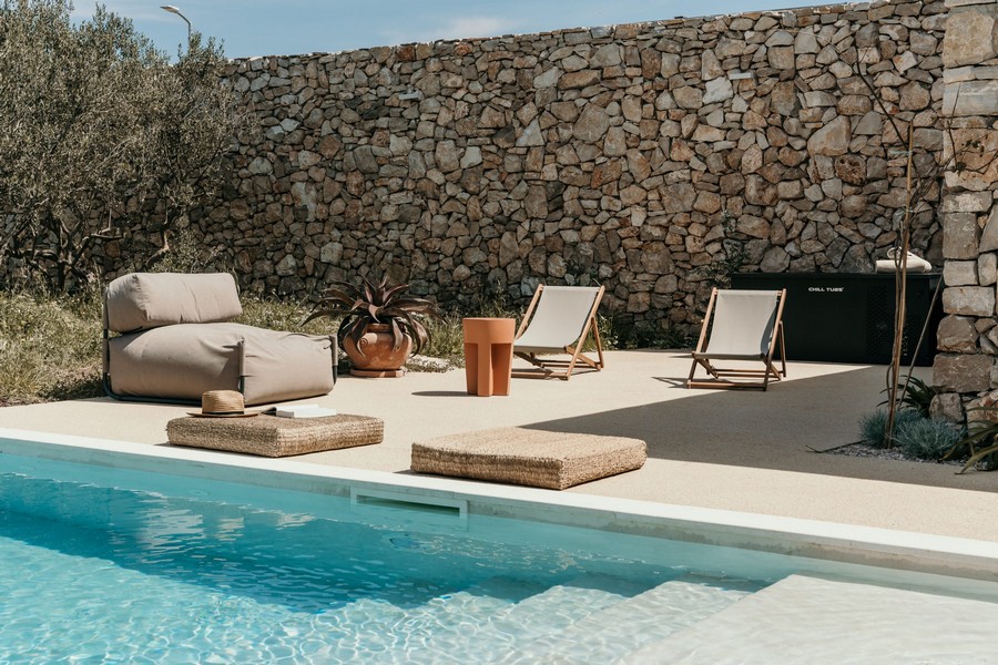Espace piscine avec bains de soleil et mur en pierre naturelle