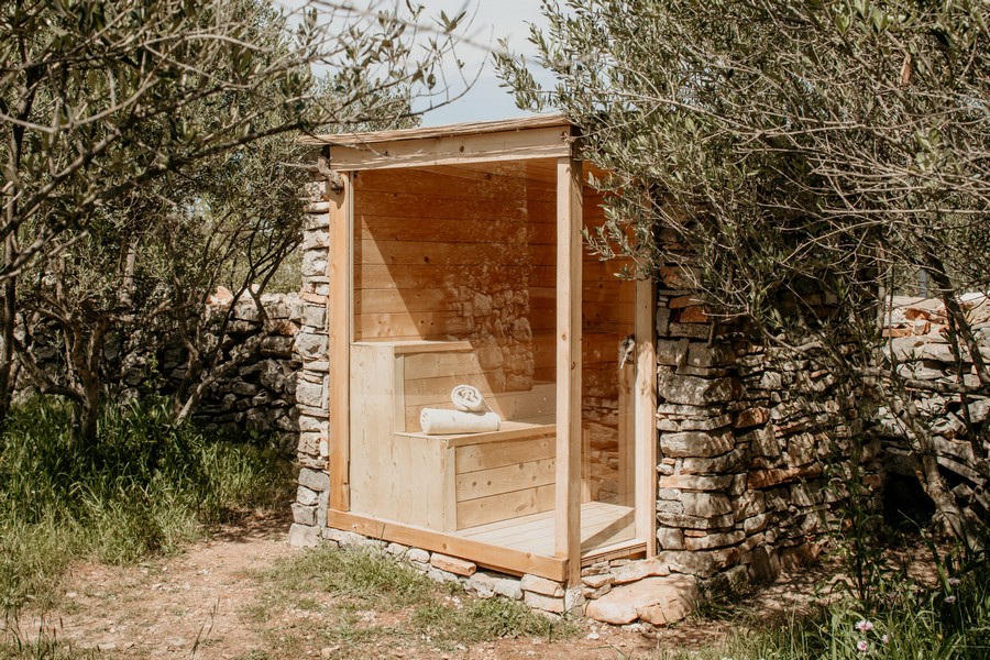 Sauna extérieur dans le jardin avec pierre naturelle et revêtement en bois