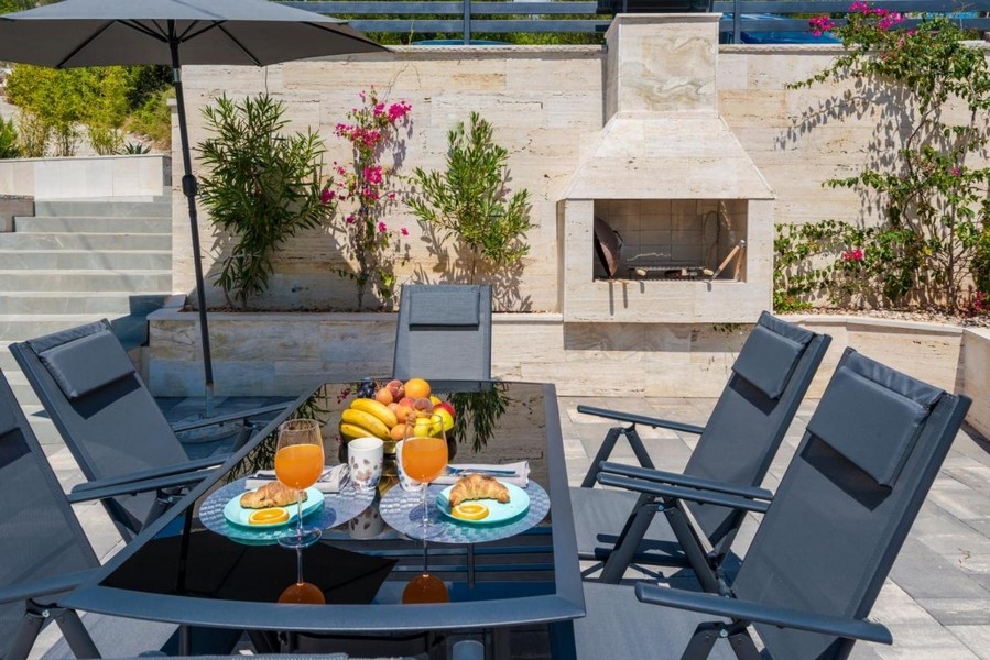 Terrasse avec salon de jardin, grill et plantes méditerranéennes