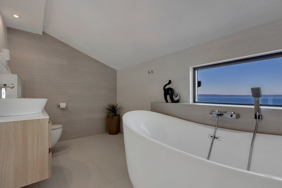 Salle de bains moderne avec baignoire îlot et vue mer