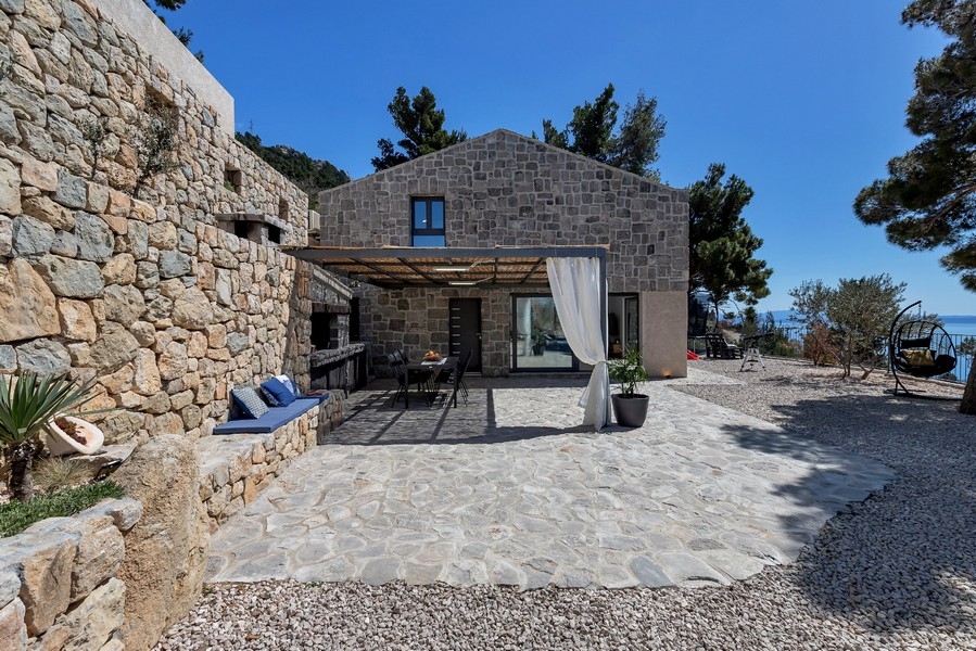 Maison en pierre avec rideaux à la pergola et cour pavée