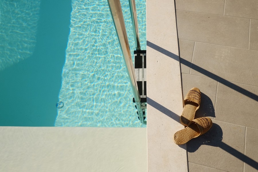 Détail de la piscine avec lumière du soleil et sandales