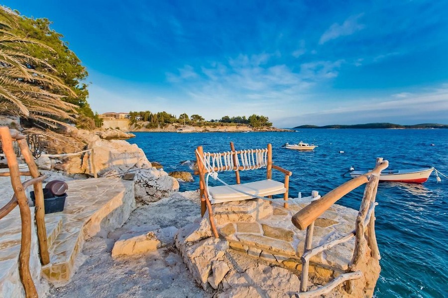 Banc en bois sur le rocher avec bateaux dans la baie