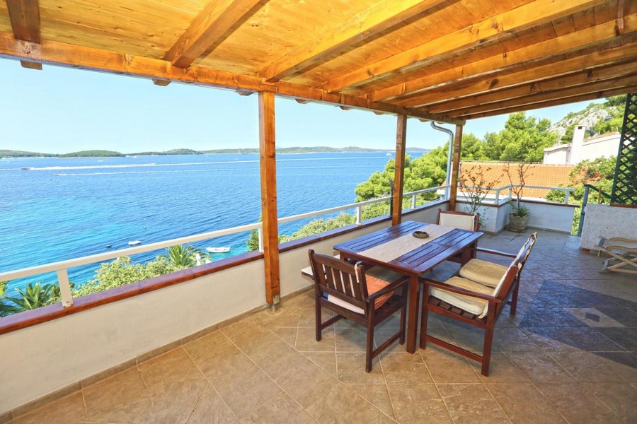 Terrasse couverte avec table à manger et vue mer