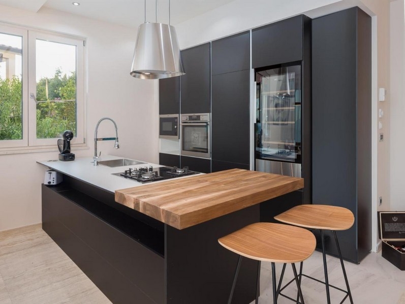 Cuisine moderne noire avec îlot de cuisson et comptoir en bois