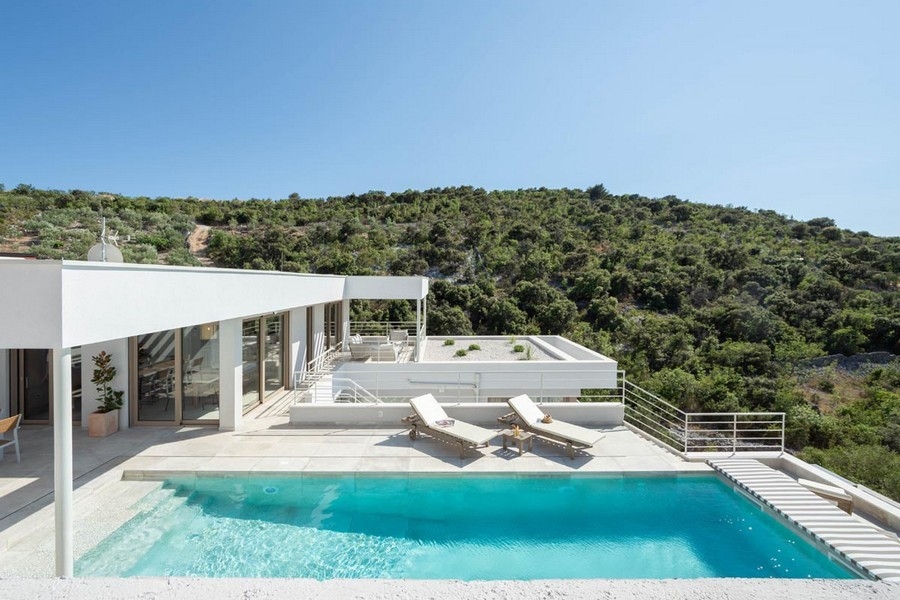 Maison blanche avec piscine et transats devant le versant végétalisé