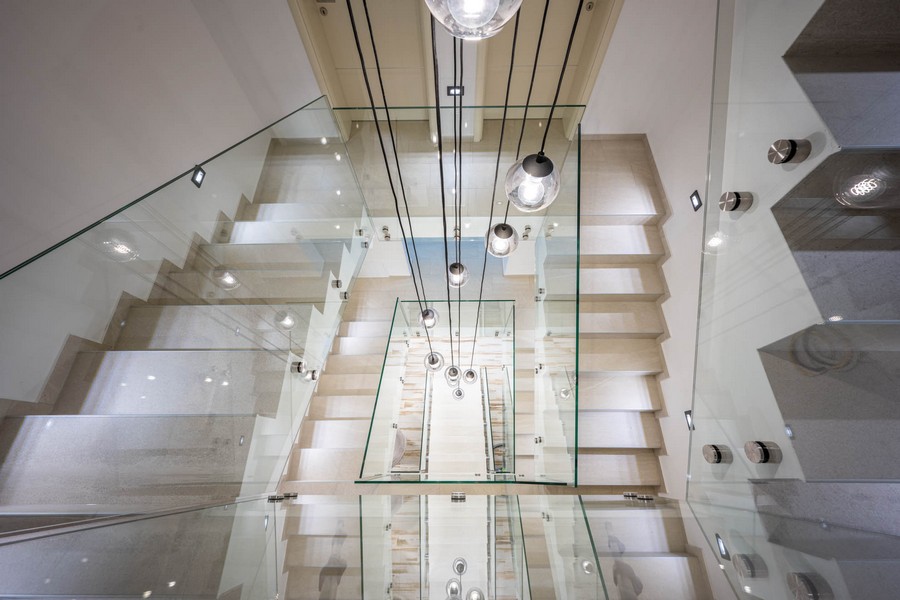 Cage d'escalier avec garde-corps en verre et luminaires design