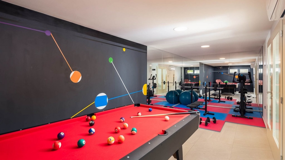 Salle de loisirs et de fitness avec table de billard et appareils d'entraînement