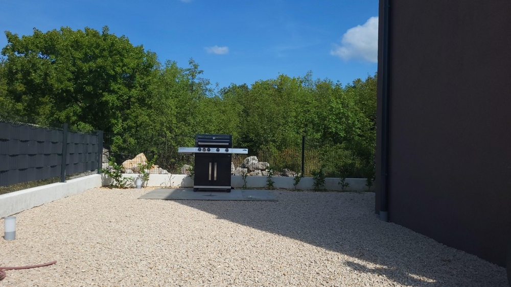 Coin grill dans le jardin avec sol en pierre naturelle