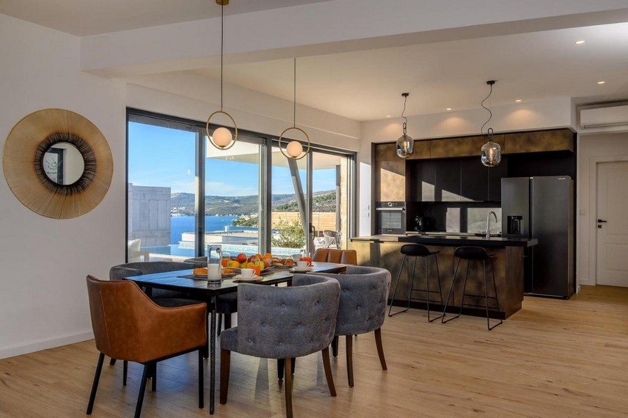 Coin repas à côté de la cuisine avec vue sur la piscine et la mer