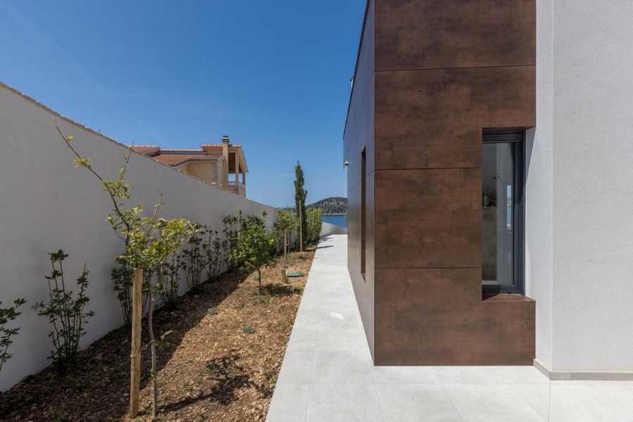 Vue latérale de la villa avec allée de jardin et vue mer